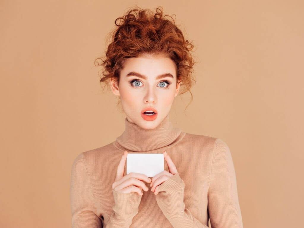 Attractive orange haired girl holding a business card
